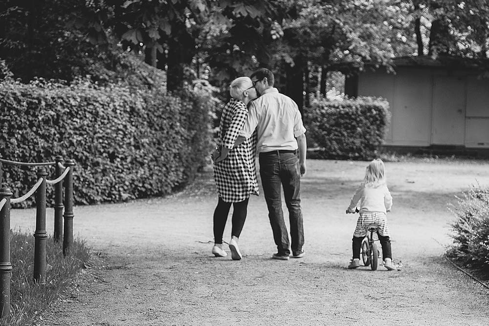 küssende Eltern beim Spaziergang mit Kind - Familienfoto, Familienglück, Familienfotografie, Familienbilder