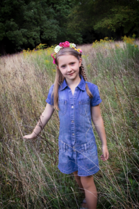 Portrait von Mädchen mit Blumenband im Haar geht über eine hochstehende Wiese - Kinderfotos, Kinderfotografie, Kinderportrait, Familienfotos, Familienfotografie