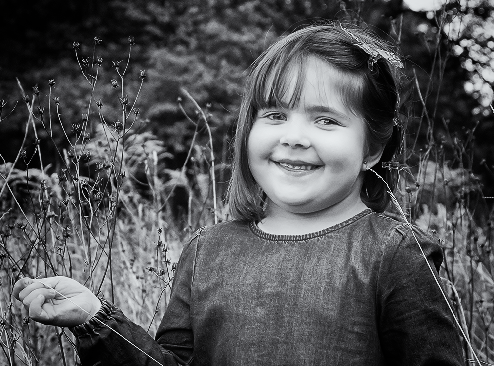 kleines Mädchen in Schwarzweiß in einer hohen Wiese stehend - Familienfotografie, Familienportrait, Familienbilder, Familienfotos, Kinderfotos, Kinderfotografie