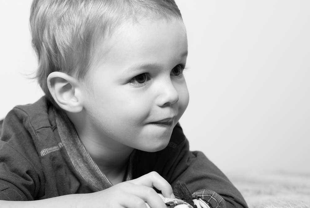 Schwarzweißportrait von kleinem Jungen auf Decke - Kinderportrait, Familienfotos, Familienfotografie, Kinderfotografie, Kinderfotos